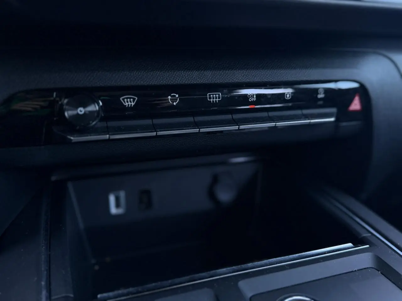Détail de la console centrale noire du Citroën C5 Aircross Hybrid 2025 avec commandes climatisation et prises USB visibles.
