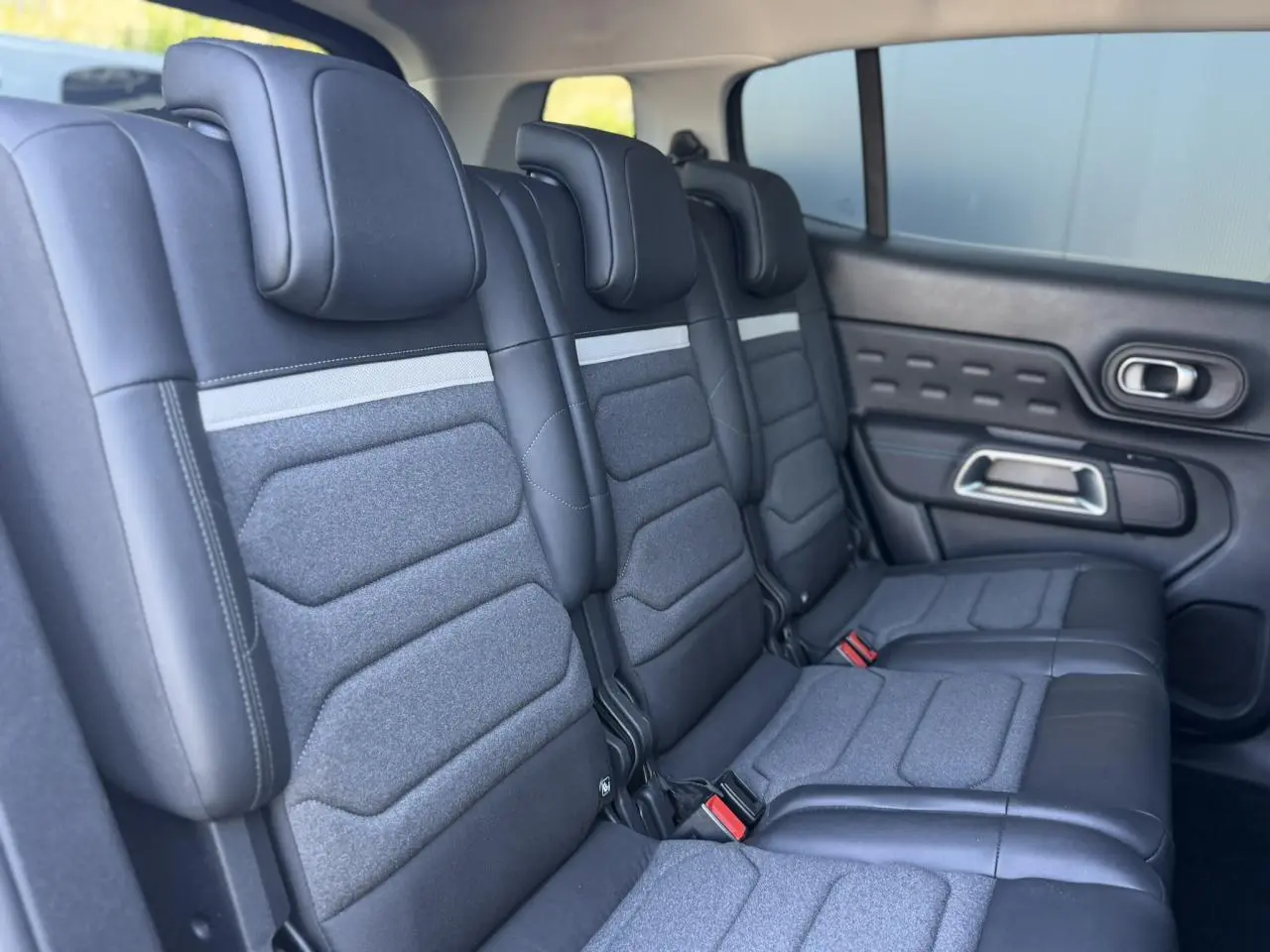 Vue latérale droite des trois sièges arrière indépendants gris foncé du Citroën C5 Aircross Hybrid 2025 avec appuis-tête réglables.