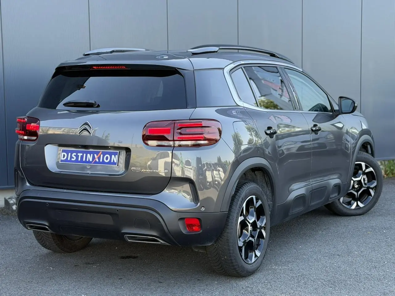 Vue 3/4 arrière droite d'un Citroën C5 Aircross Hybrid gris Platinium avec jantes alliage bi-ton et hayon électrique.