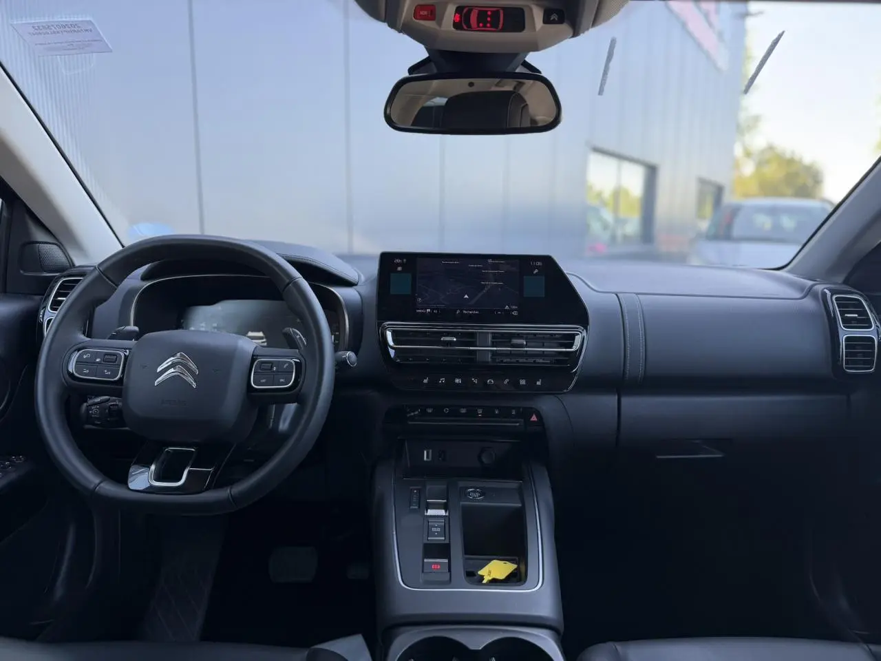 Vue intérieure avant du Citroën C5 Aircross Hybrid gris Platinium, volant multifonction et écran tactile central.