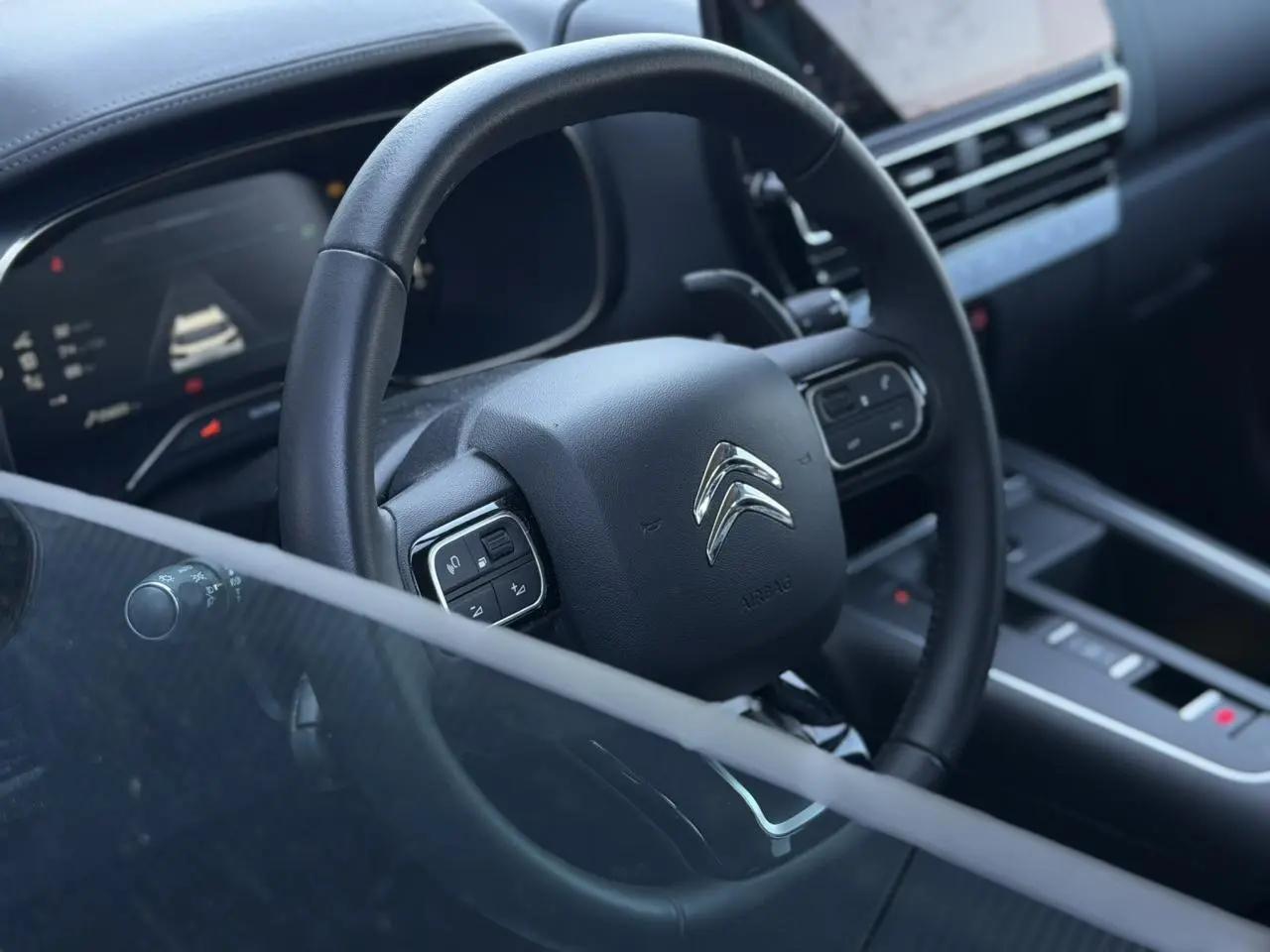 Vue rapprochée du volant cuir noir et du tableau de bord numérique du Citroën C5 Aircross Hybrid 2025.