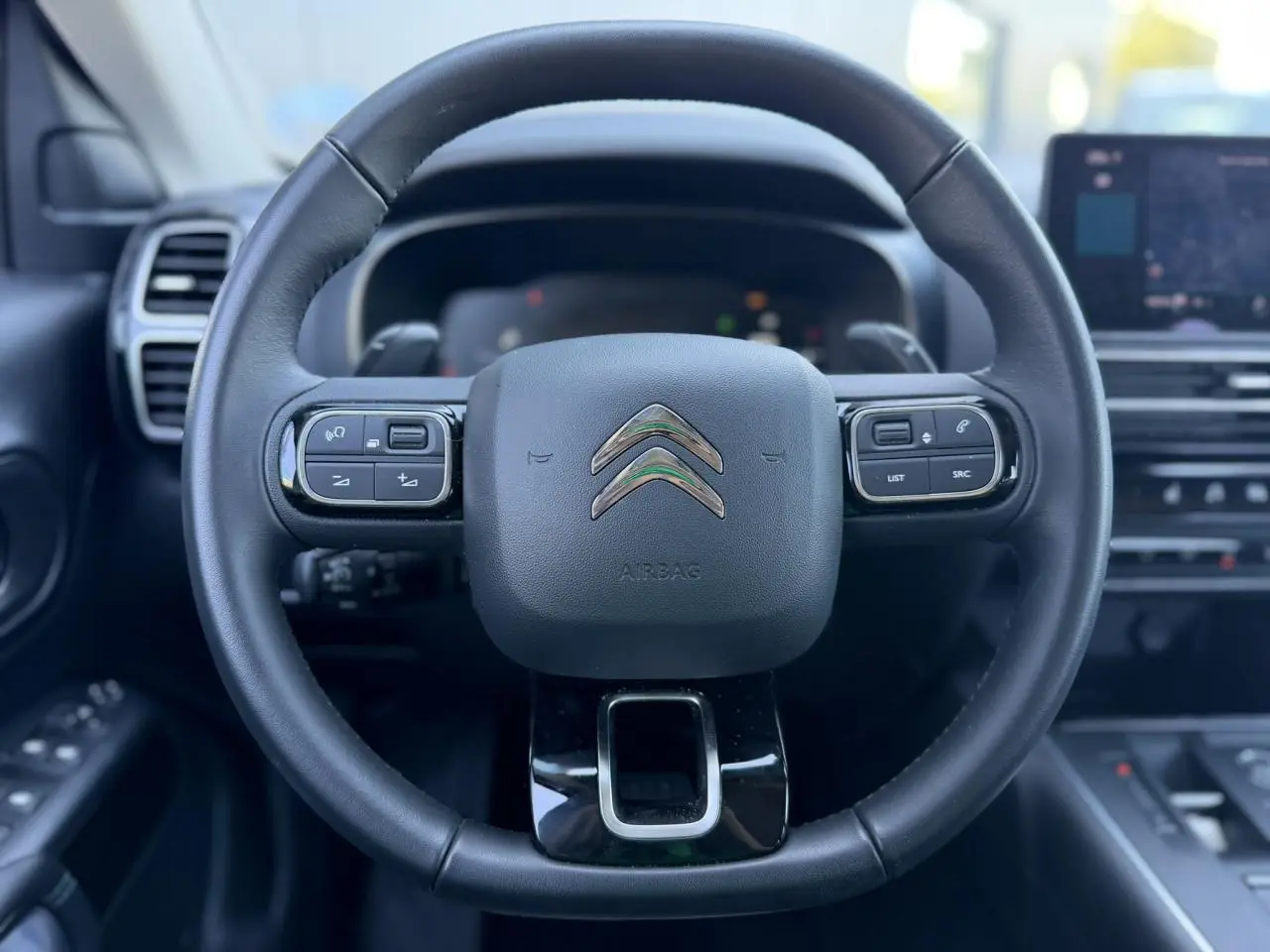 Vue rapprochée du volant cuir noir du Citroën C5 Aircross 2025 avec commandes intégrées et logo chromé central.