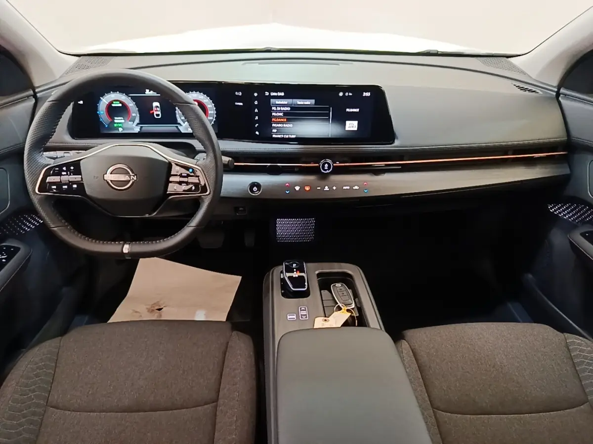 Vue intérieure avant du Nissan Ariya noir 2026, tableau de bord moderne avec écran tactile large et volant multifonctions cuir.