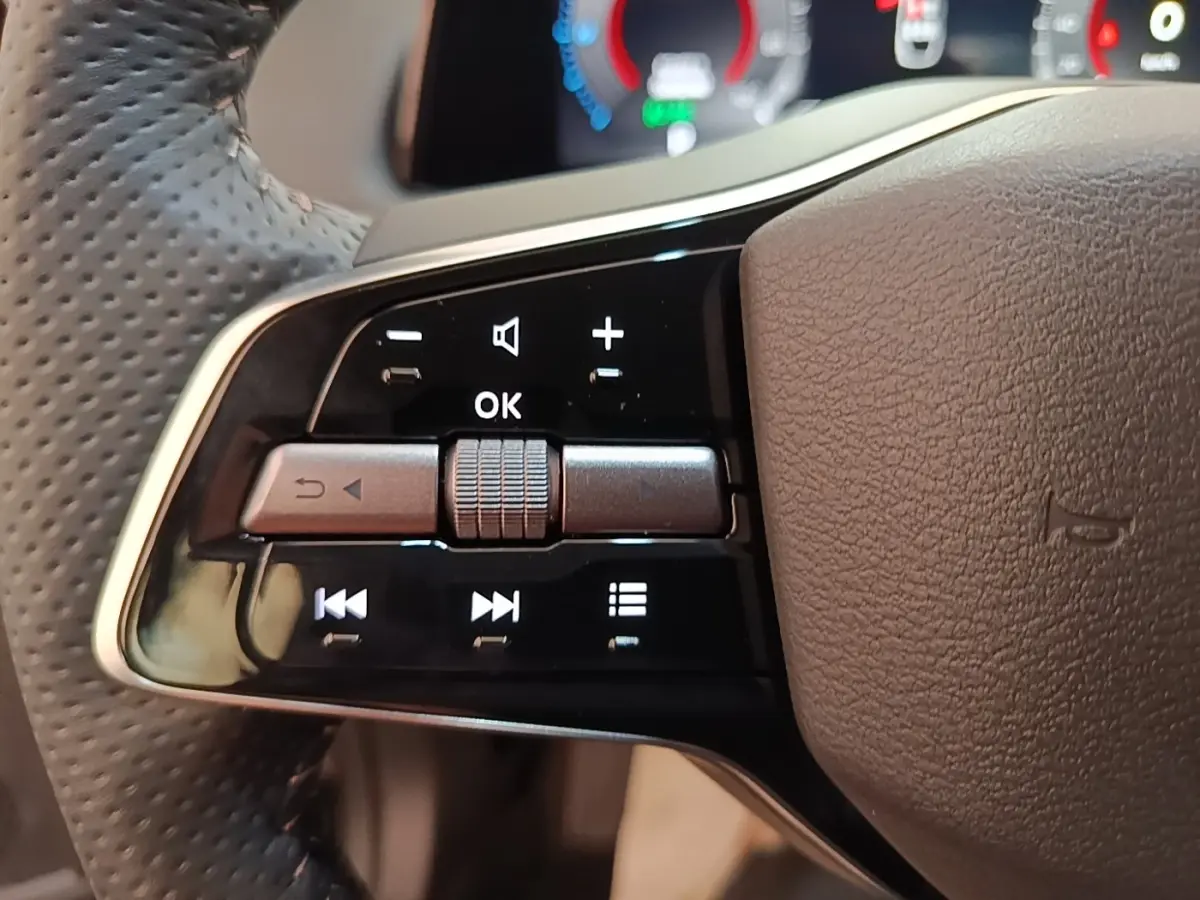 Gros plan sur les commandes gauche du volant cuir noir perforé du Nissan Ariya 63kWh 218ch Engage 2026.
