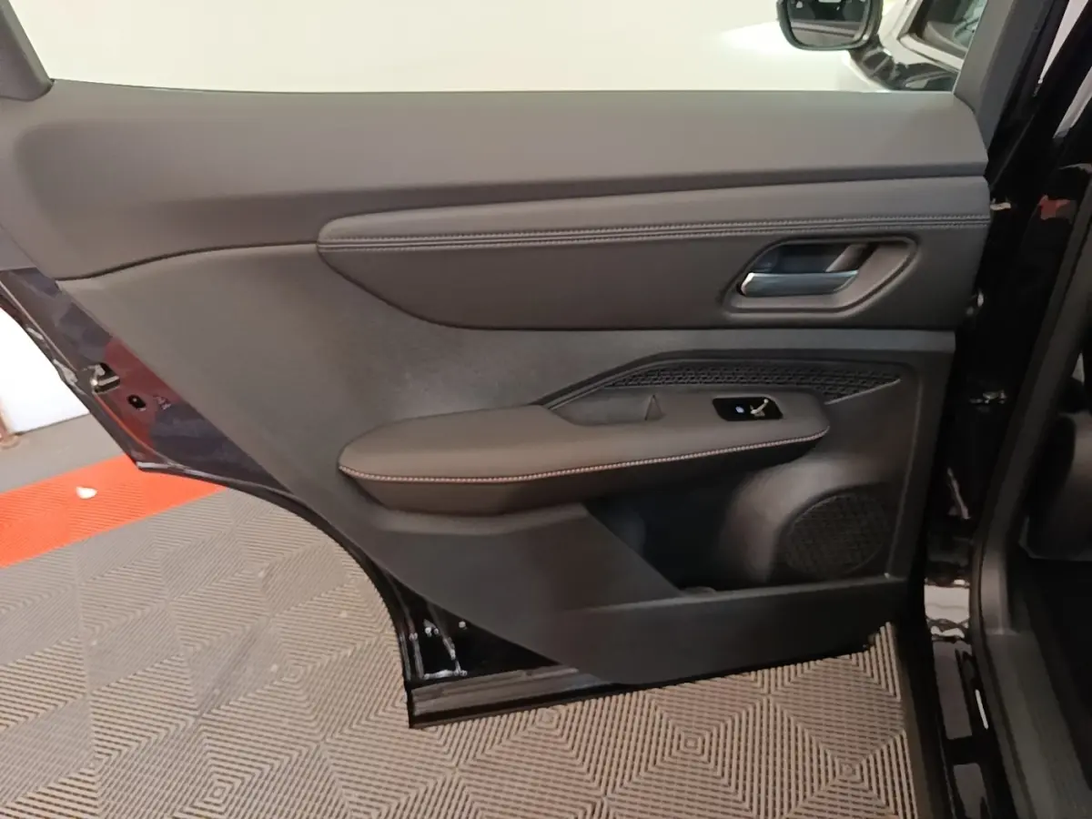 Vue intérieure du panneau de porte arrière droite noir du Nissan Ariya 63kWh 218ch Engage avec accoudoir cuir et commande de vitre.