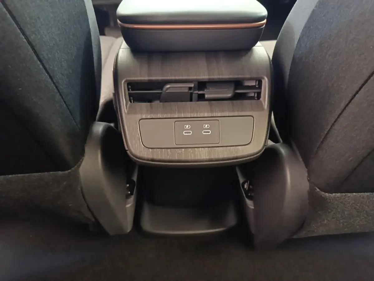 Vue rapprochée de la console arrière noire du Nissan Ariya 63kWh avec prises USB-C et aérateurs.