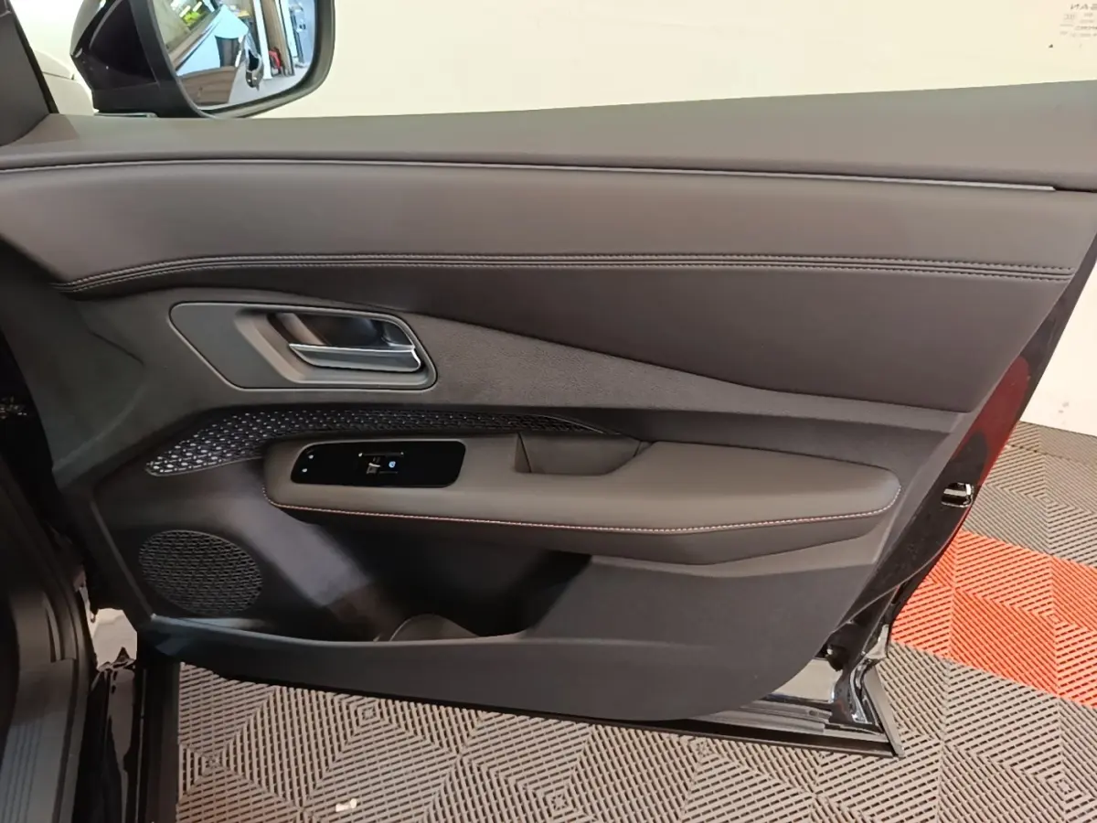 Vue côté gauche de la porte avant noire du Nissan Ariya 63kWh 218ch Engage avec garniture cuir et commandes électriques.