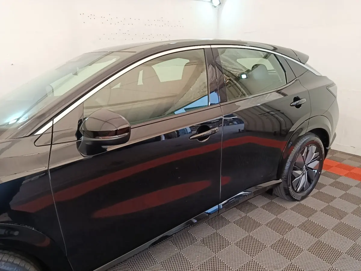 Vue latérale côté gauche du Nissan Ariya noir 63kWh 218ch Engage avec jantes modernes et rétroviseur électrique.