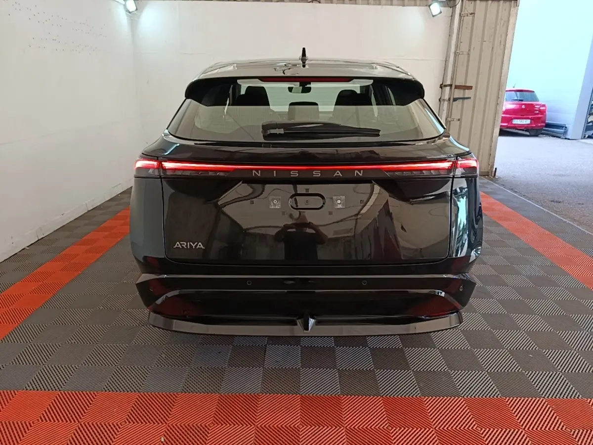 Vue arrière d'un Nissan Ariya noir avec feux arrière LED continus et logo Nissan lumineux.
