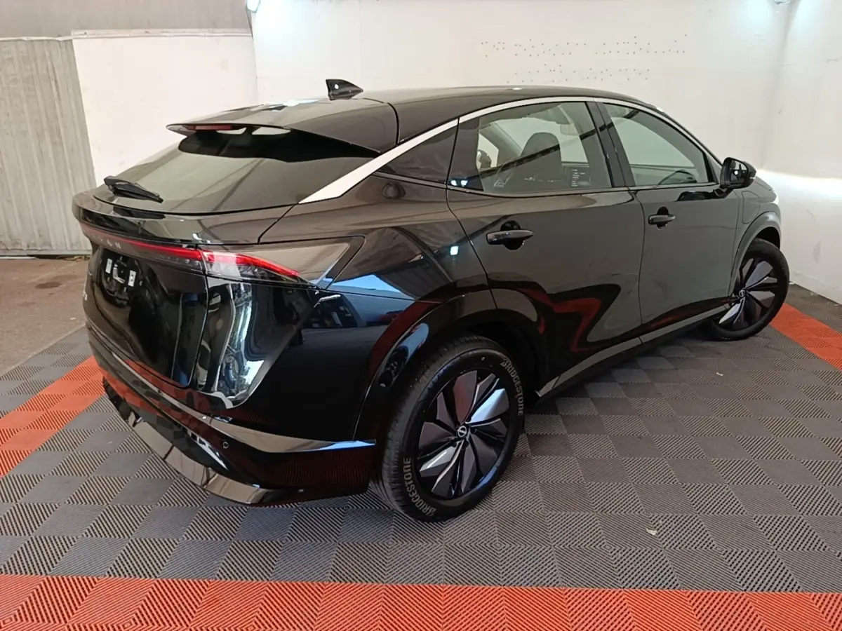 Nissan Ariya 63kWh noir, vue 3/4 arrière droit, feux arrière LED et jantes aérodynamiques visibles.