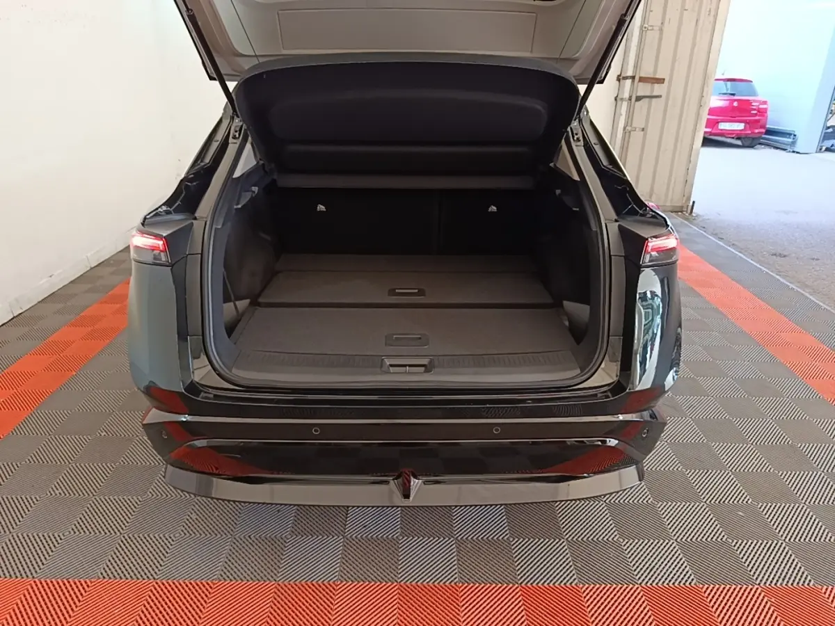 Vue arrière d'un Nissan Ariya noir 2026 avec coffre ouvert et banquette arrière rabattue dans un garage.