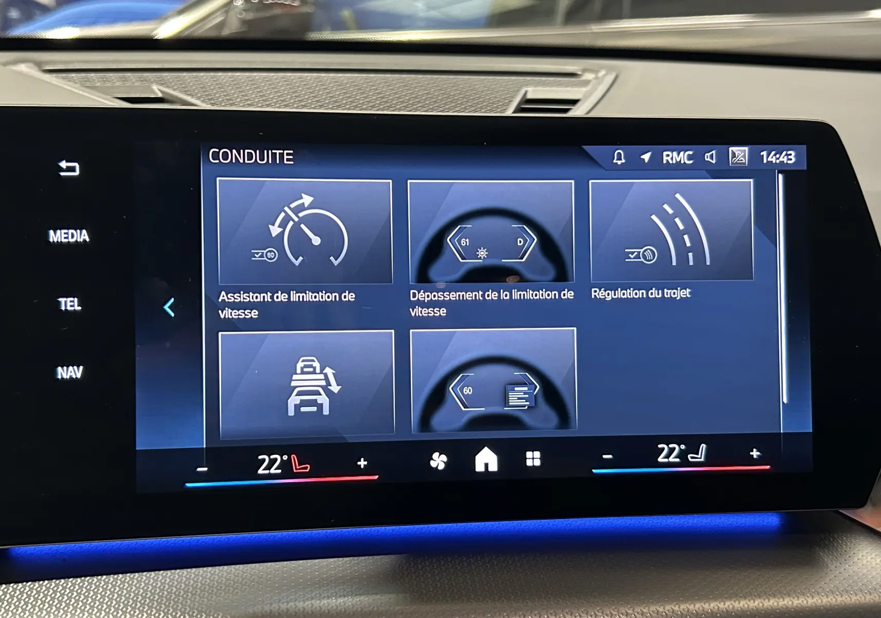 Écran tactile central du BMW X1 Spacesilber 2024 affichant les aides à la conduite avec interface moderne et éclairage d'ambiance bleu.