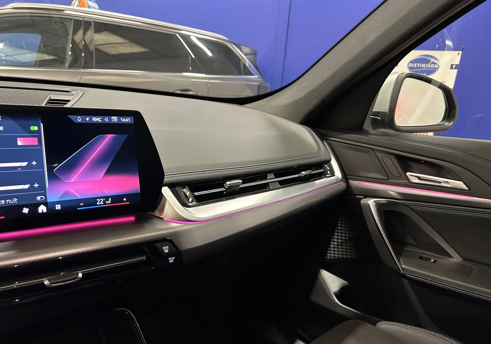 Tableau de bord et porte côté droit du BMW X1 2024 M Sport avec éclairage d'ambiance violet et écran tactile.