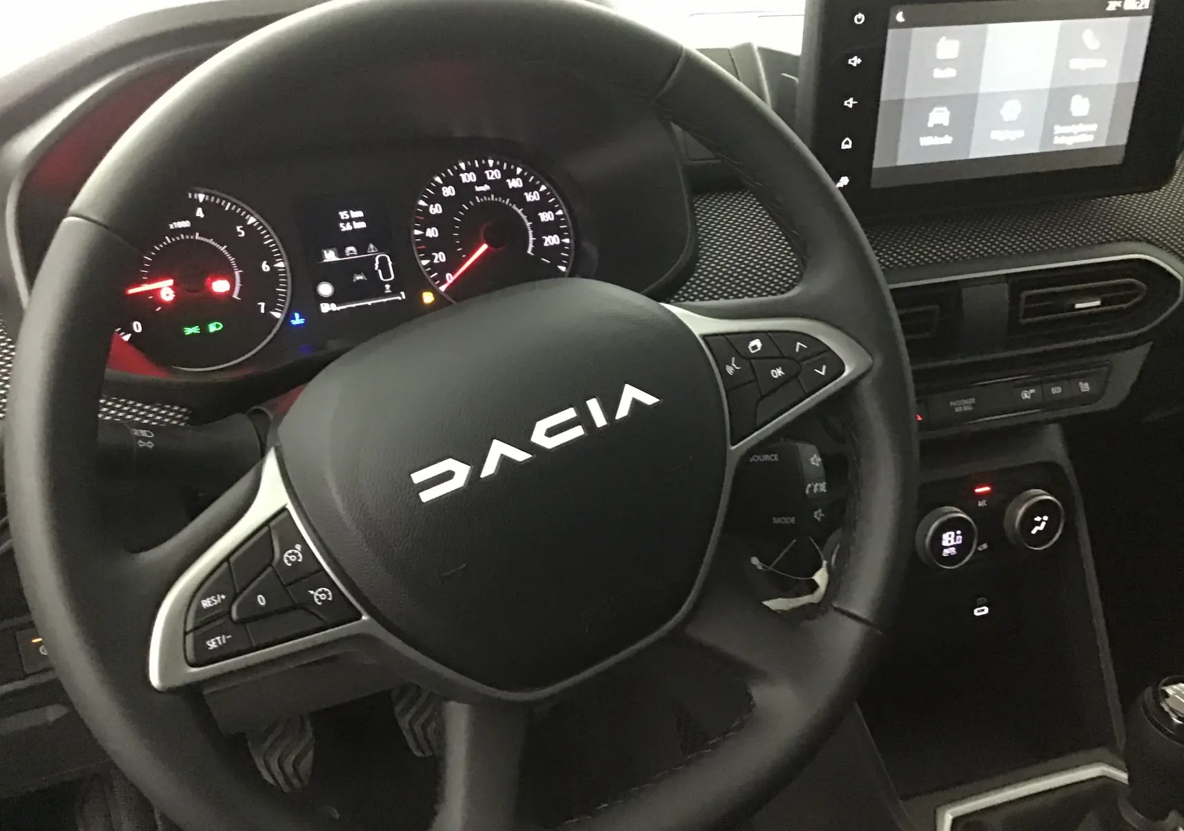 Vue rapprochée du volant noir de la Dacia Sandero Stepway 2025 avec tableau de bord et écran tactile visible.