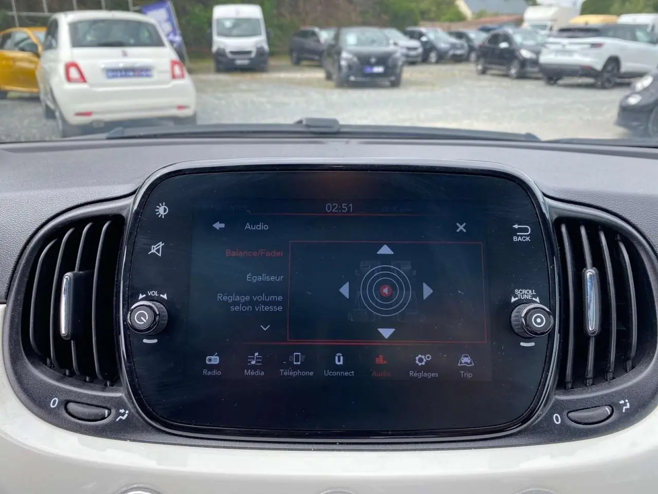 Écran tactile central de la Fiat 500 blanche 2024 montrant les réglages audio avec aérateurs latéraux noirs.