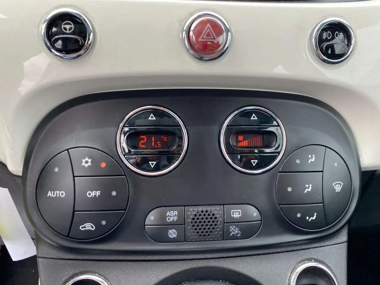 Tableau de bord de Fiat 500 2024 blanc, vue rapprochée des commandes de climatisation automatique et boutons fonctionnels.