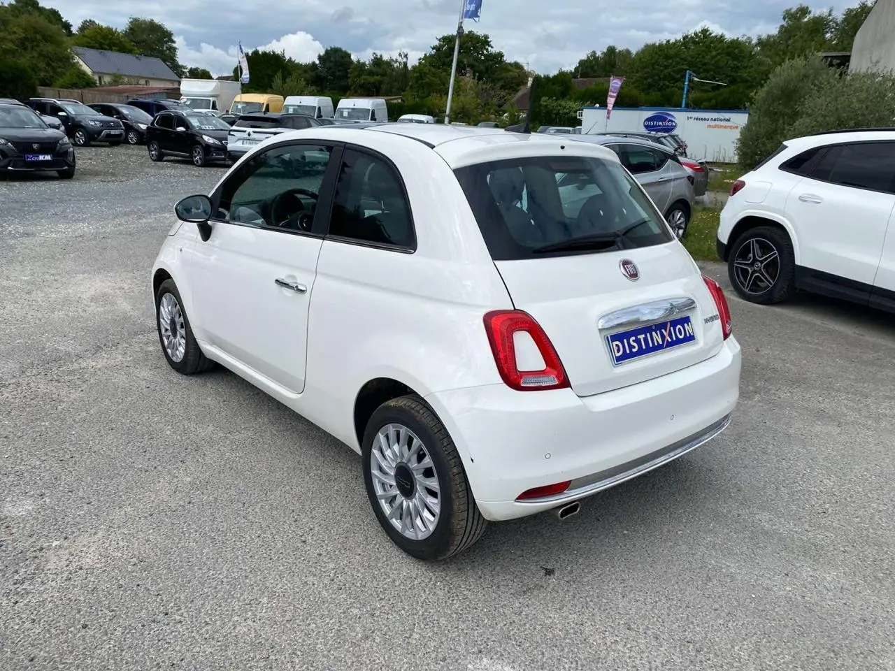 Vue 3/4 arrière droite d'une Fiat 500 blanche 2024 avec jantes alliage 16'' Spider et toit panoramique fixe.