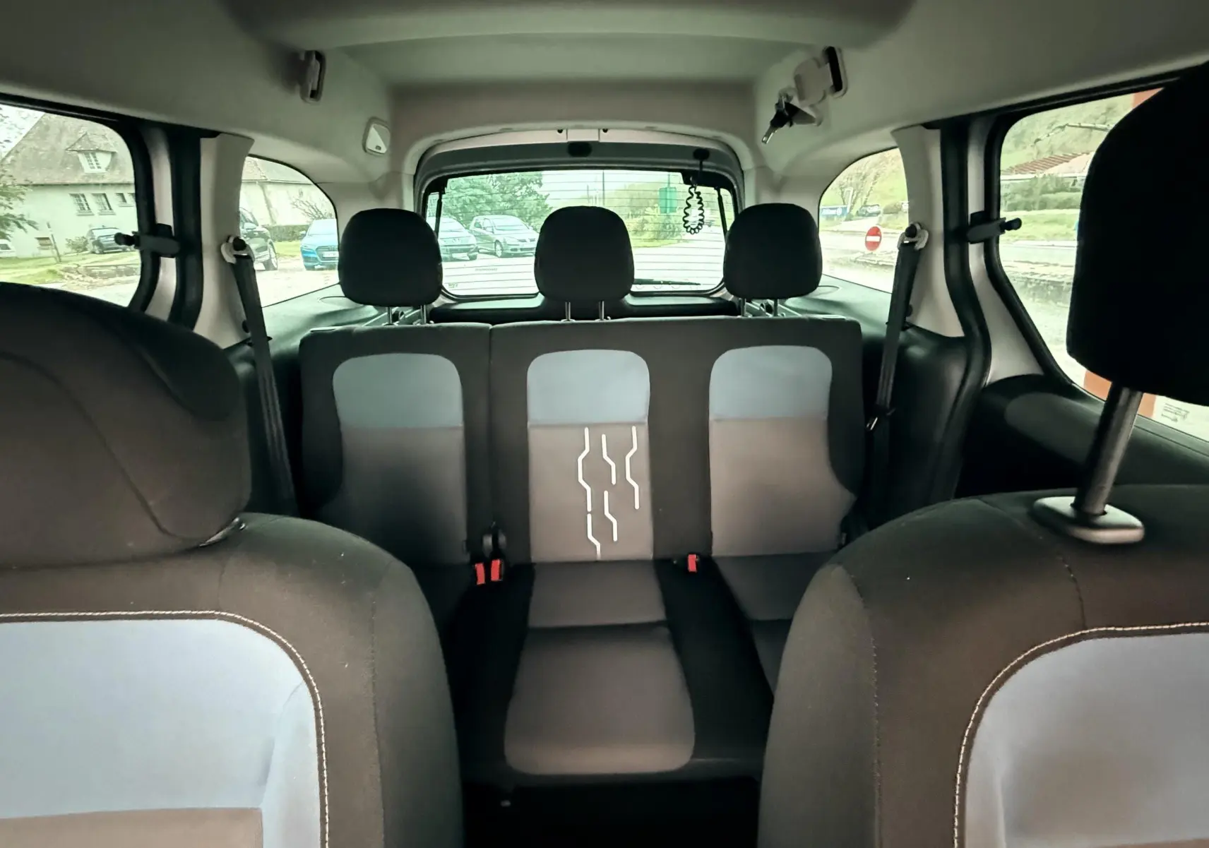 Vue intérieure arrière du Peugeot Partner Tepee 2014, sièges tissu noir et gris avec motifs blancs au centre.