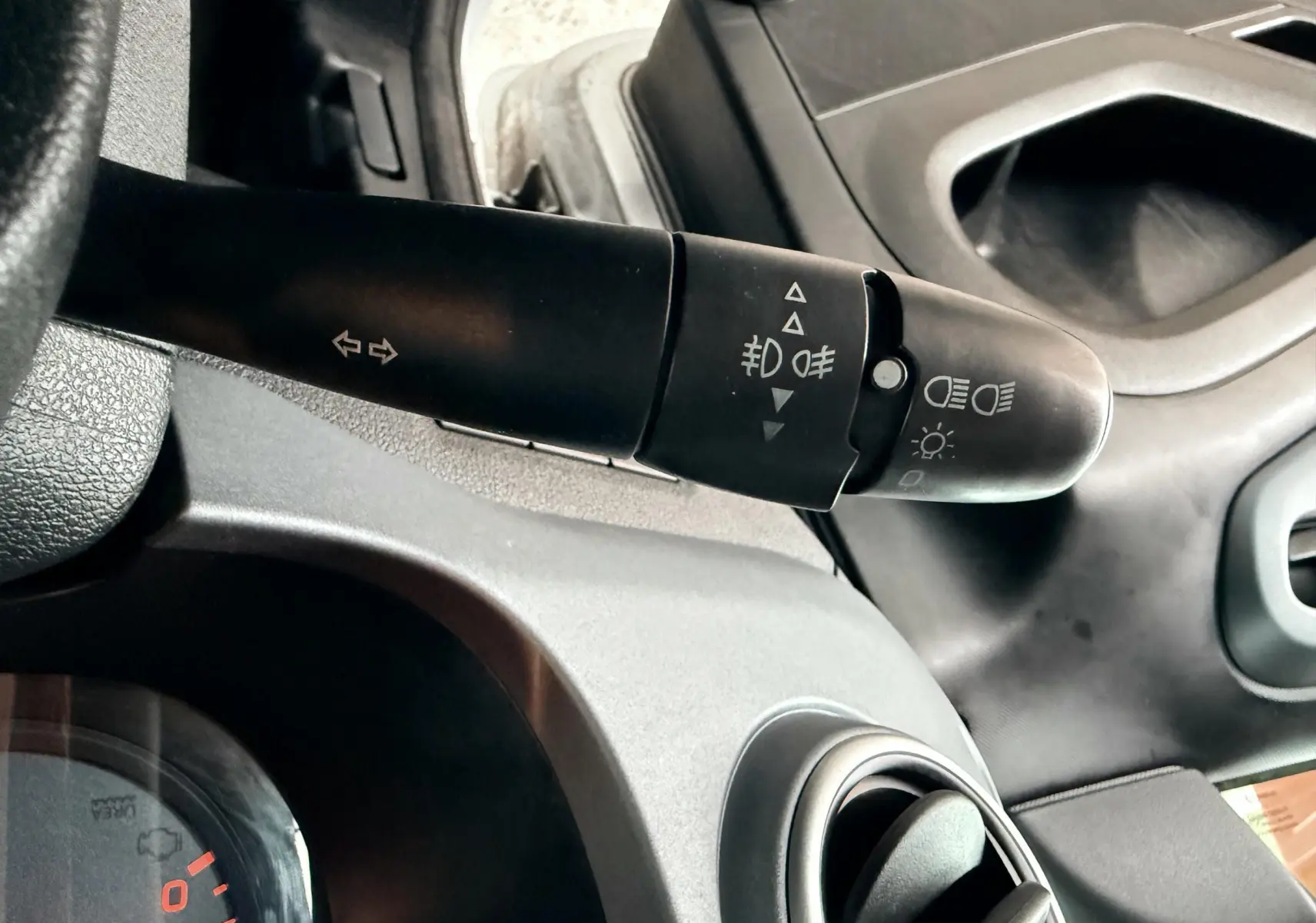 Gros plan sur la commande des phares et clignotants côté gauche du tableau de bord gris du Peugeot Partner Tepee 2014.