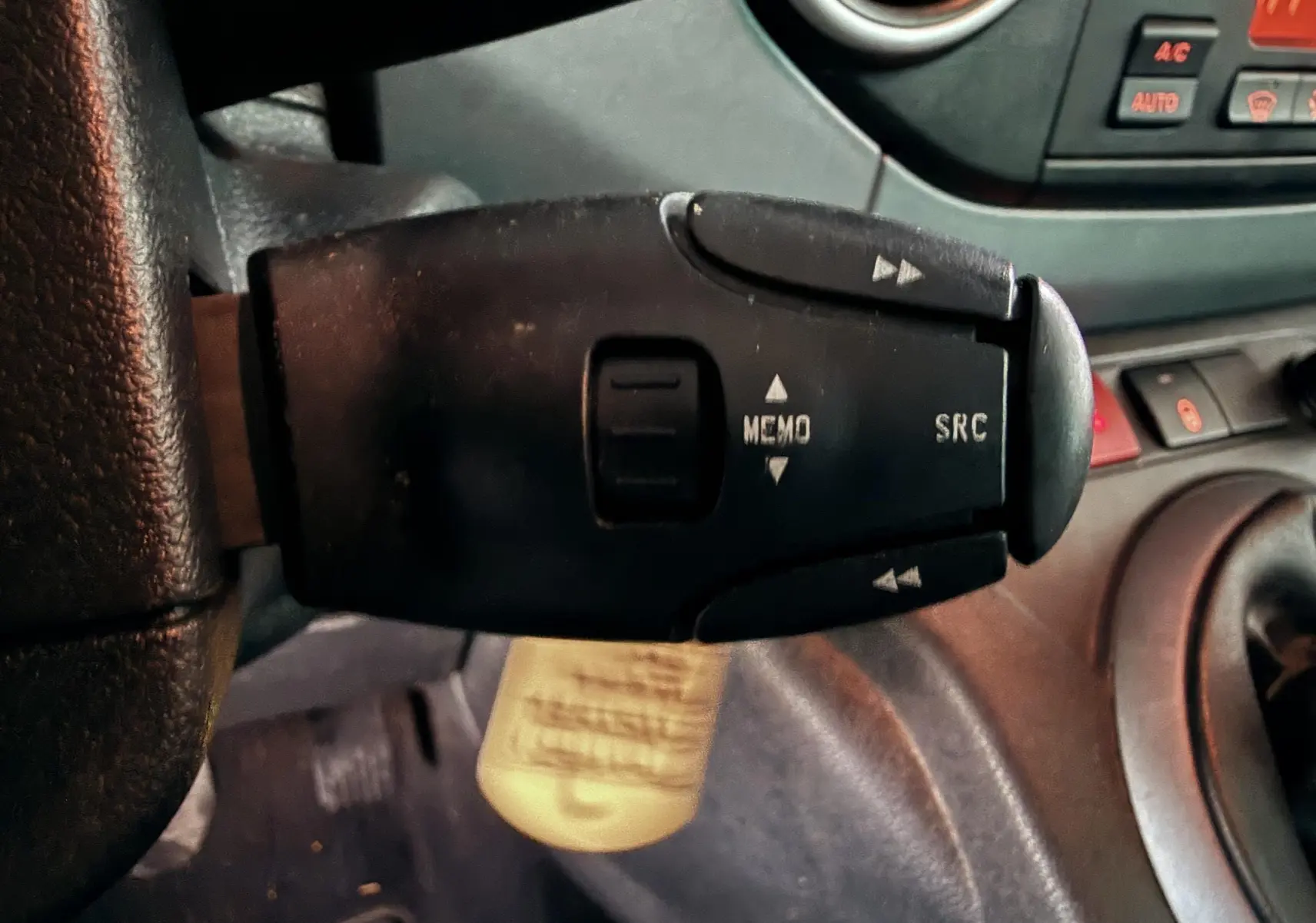 Gros plan sur la commande au volant noire avec boutons MEMO et SRC dans l'habitacle gris noir du Peugeot Partner Tepee.