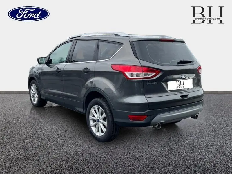 Ford Kuga gris Magnetic vu en 3/4 arrière droit, mettant en valeur ses feux arrière et jantes alu.