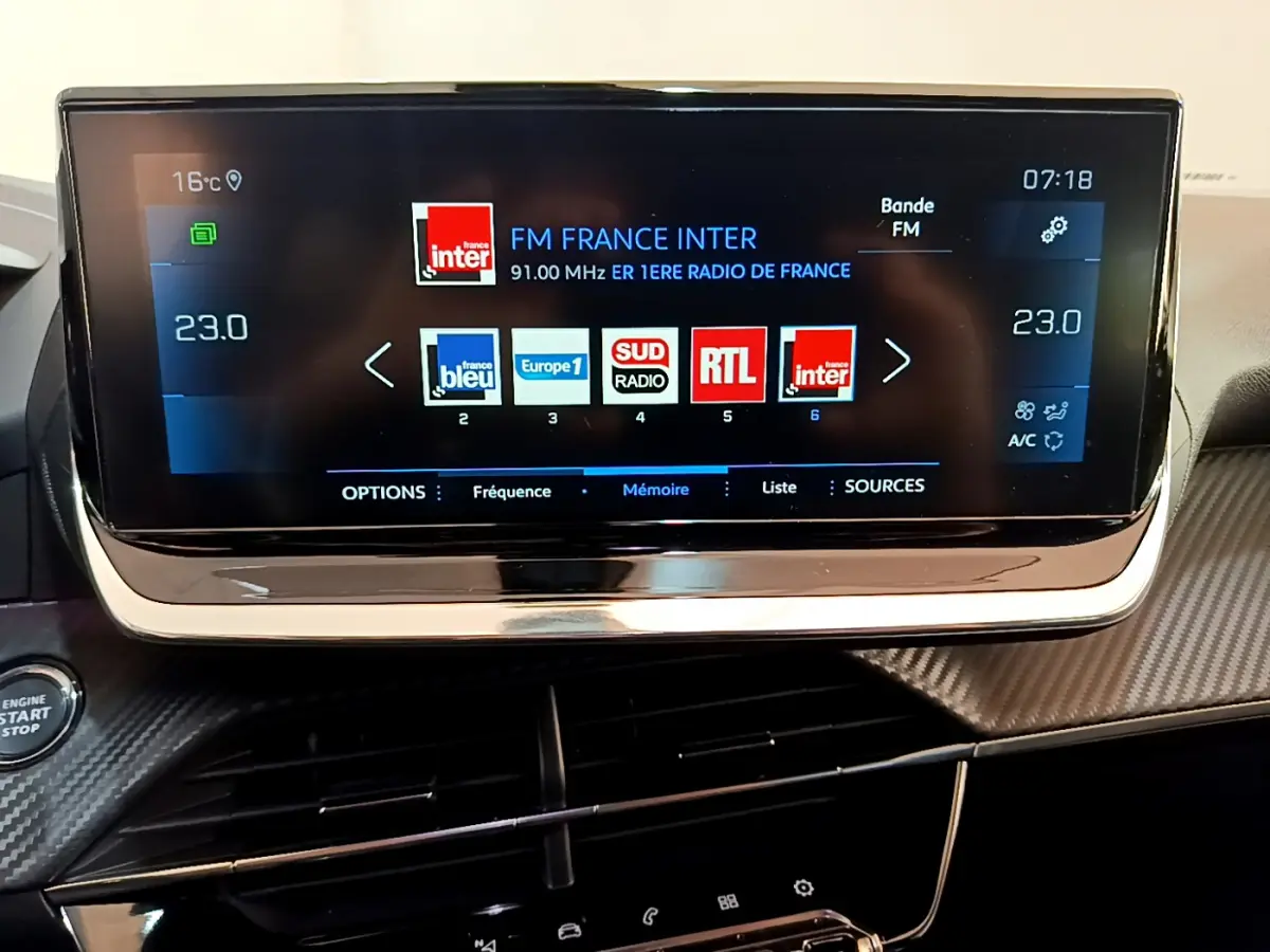 Écran tactile central du tableau de bord Peugeot 2008 gris clair, affichant les radios FM avec interface moderne.