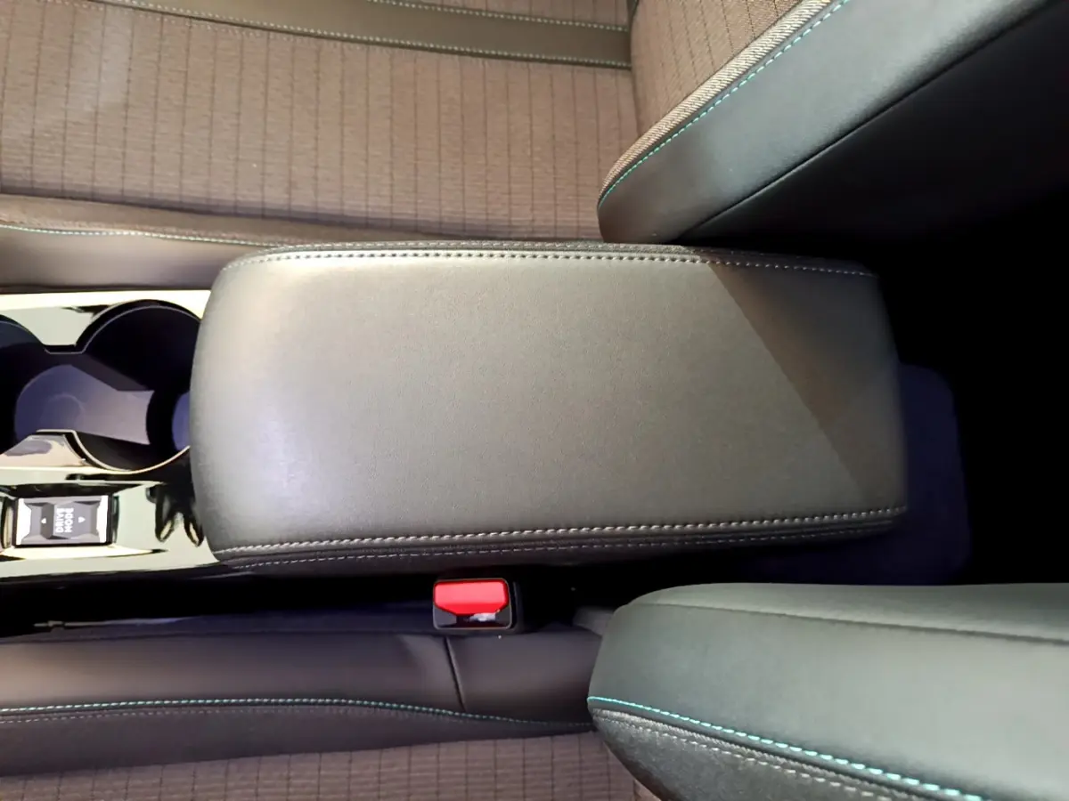 Vue plongeante sur l'accoudoir central en cuir noir et la console avec porte-gobelets du Peugeot 2008 gris clair.