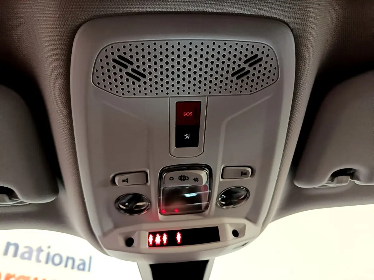 Vue en contre-plongée du plafonnier gris clair du Peugeot 2008 avec bouton SOS et éclairage intégré.