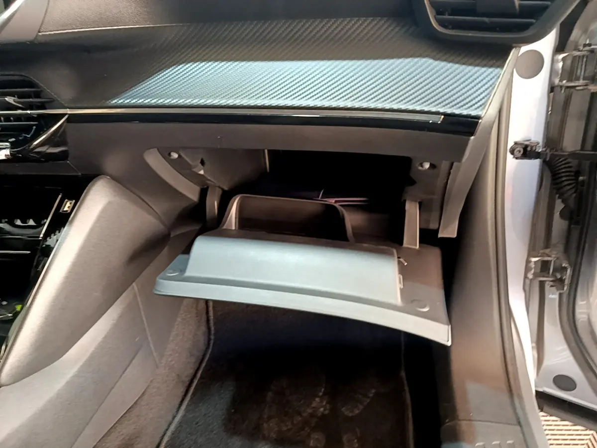 Vue intérieure côté passager du Peugeot 2008 gris clair 2021, boîte à gants ouverte sous tableau de bord.