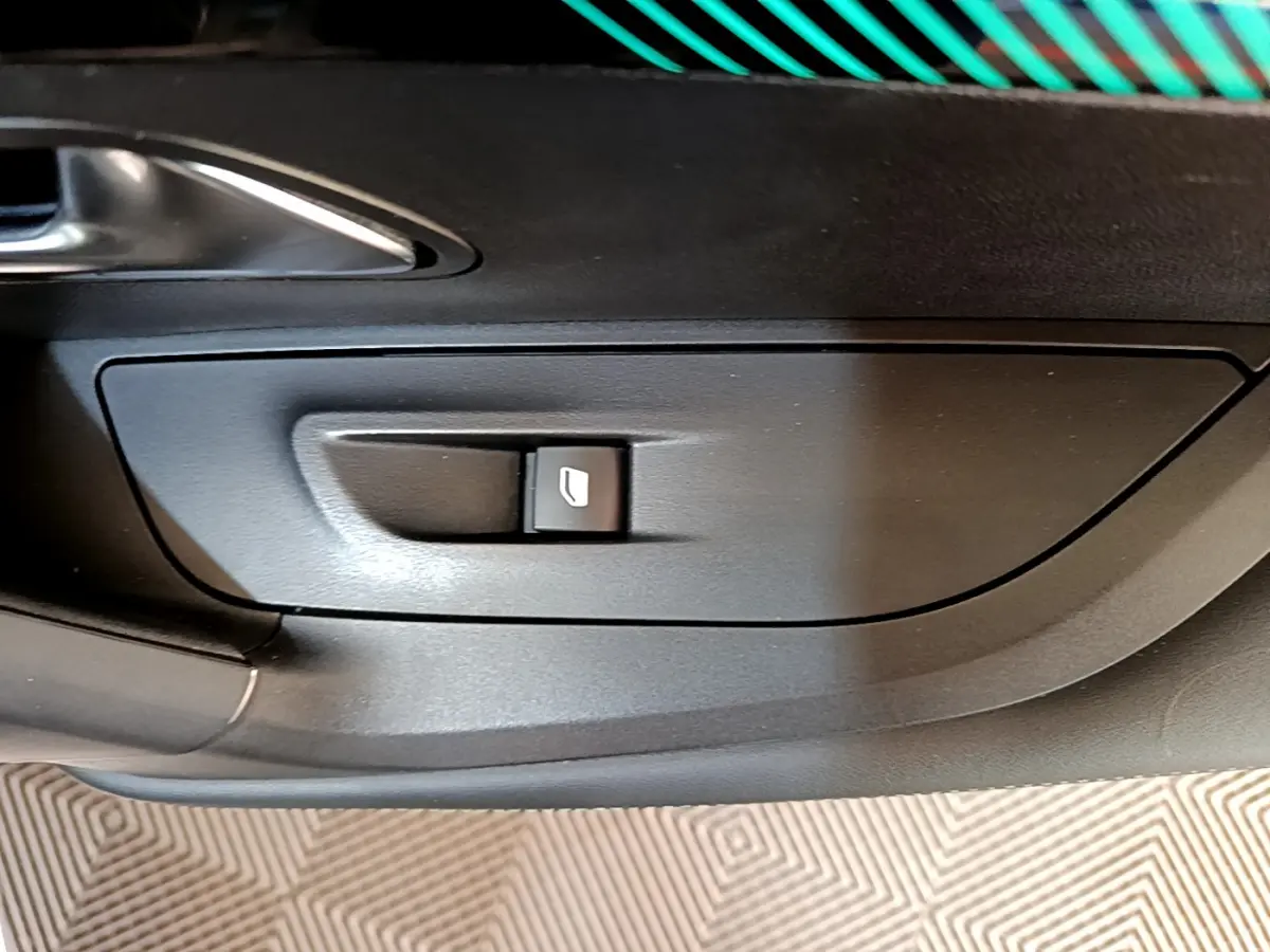 Bouton de commande de lève-vitre sur la porte intérieure côté gauche d’un Peugeot 2008 gris clair.