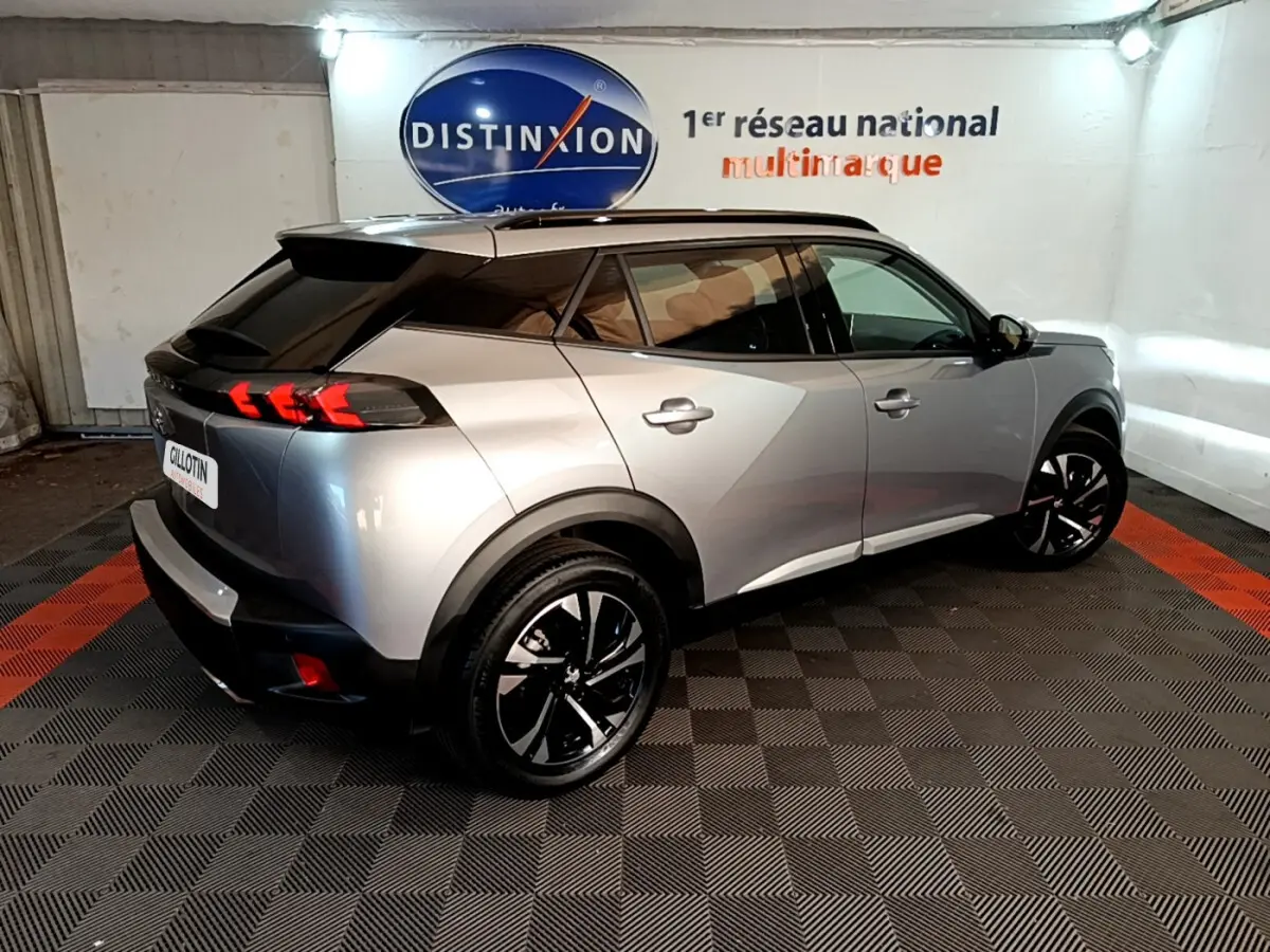 Vue 3/4 arrière droite d’un Peugeot 2008 gris clair avec feux arrière LED et jantes noires en concession.