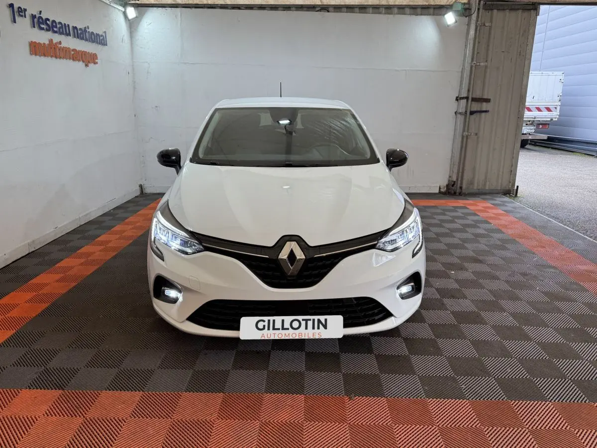 Renault Clio Business TCe 100 GPL blanc vue de face, avec phares LED allumés et logo Renault visible.