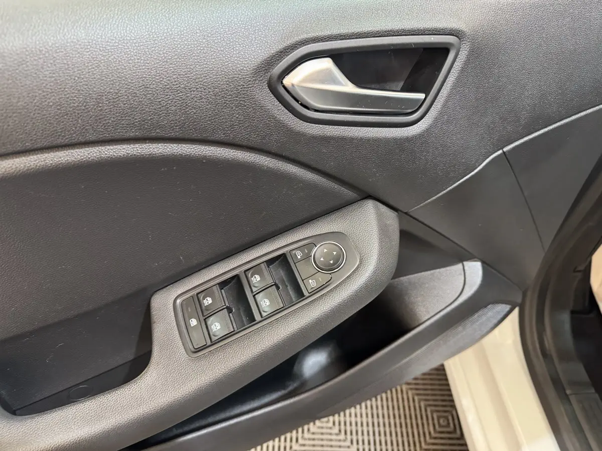 Gros plan sur la porte avant gauche de la Renault Clio Business blanche, montrant les commandes des vitres et rétroviseurs.