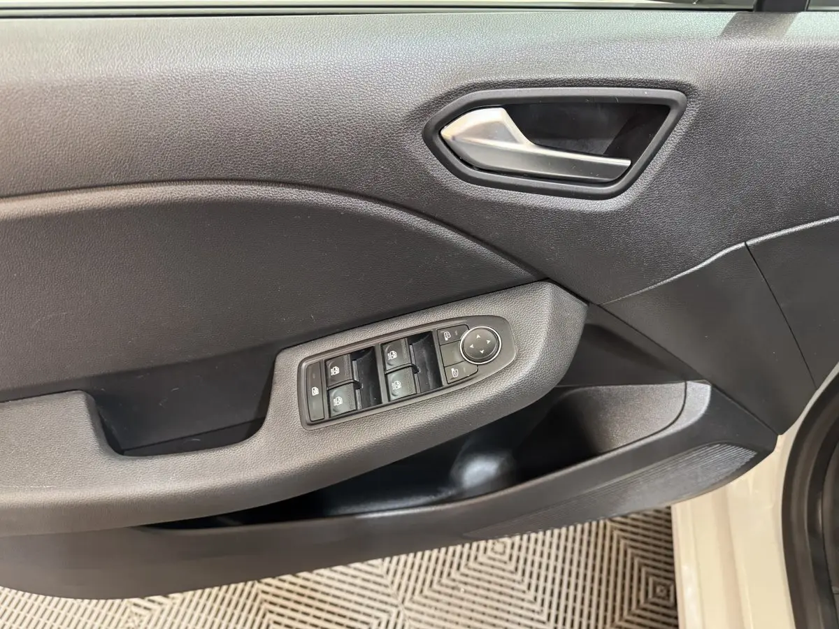 Gros plan sur la porte avant gauche noire de la Renault Clio blanche 2023 avec commandes électriques des vitres.