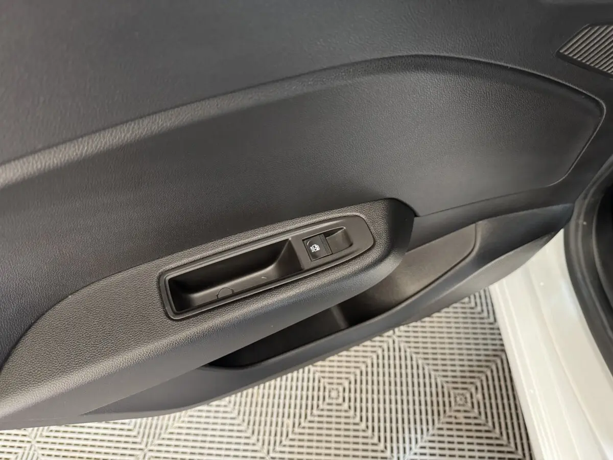 Détail de la porte intérieure côté conducteur d'une Renault Clio Business blanche, avec commande de vitre électrique.