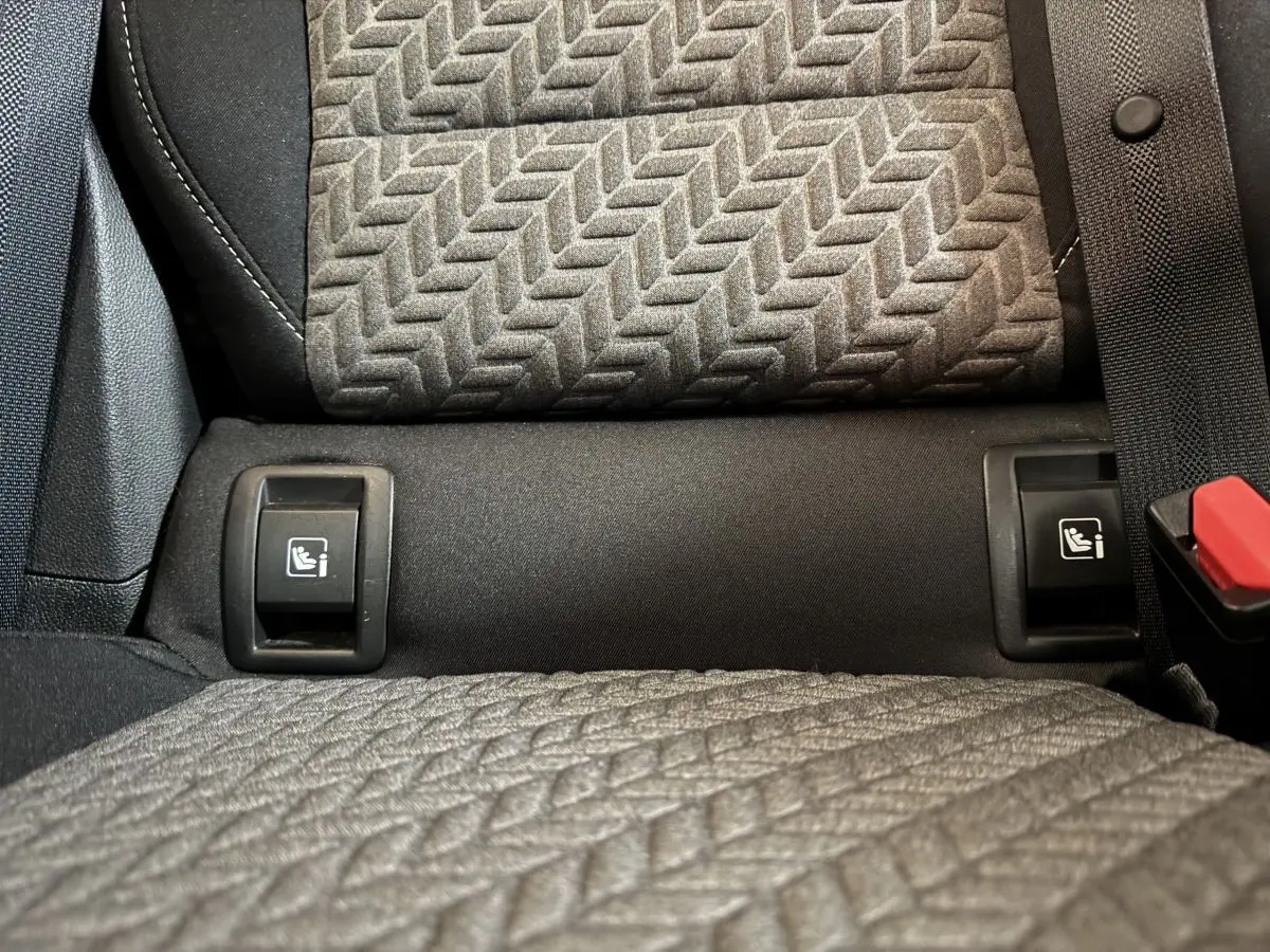 Gros plan sur les fixations Isofix entre les sièges arrière gris texturés de la Renault Clio Business blanche 2023.