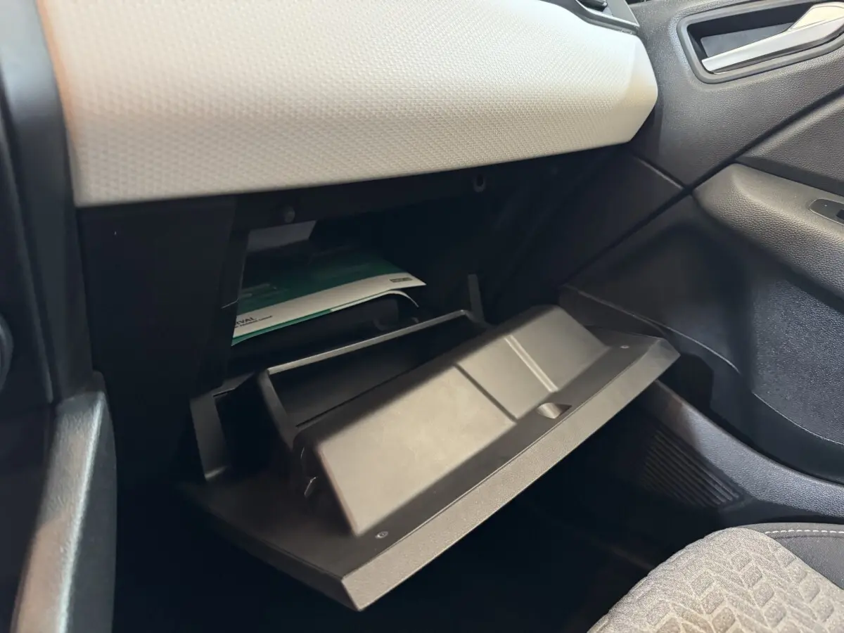 Gant de rangement ouvert côté passager dans l'habitacle d'une Renault Clio Business blanc, avec tableau de bord clair.