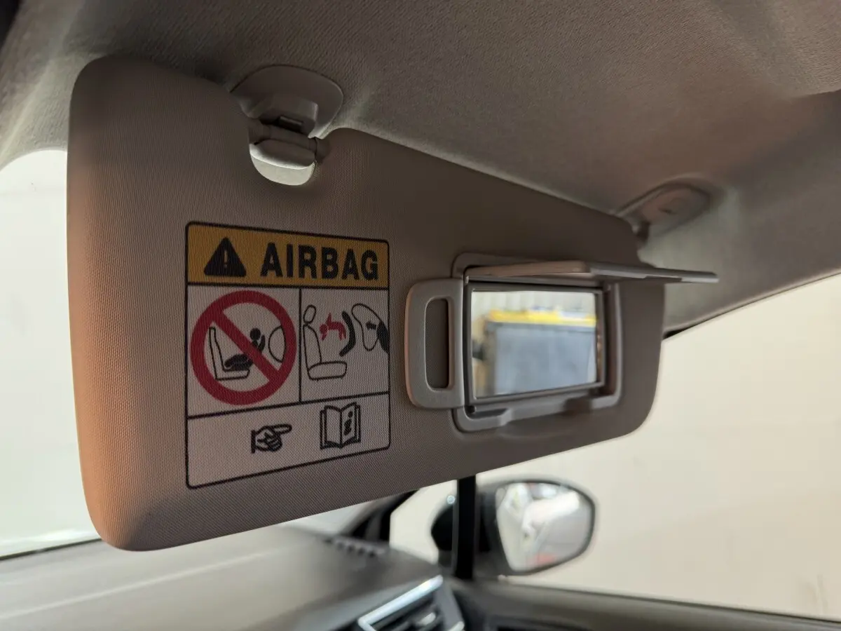 Détail du pare-soleil côté conducteur avec miroir et avertissement airbag dans Renault Clio blanc 2023.