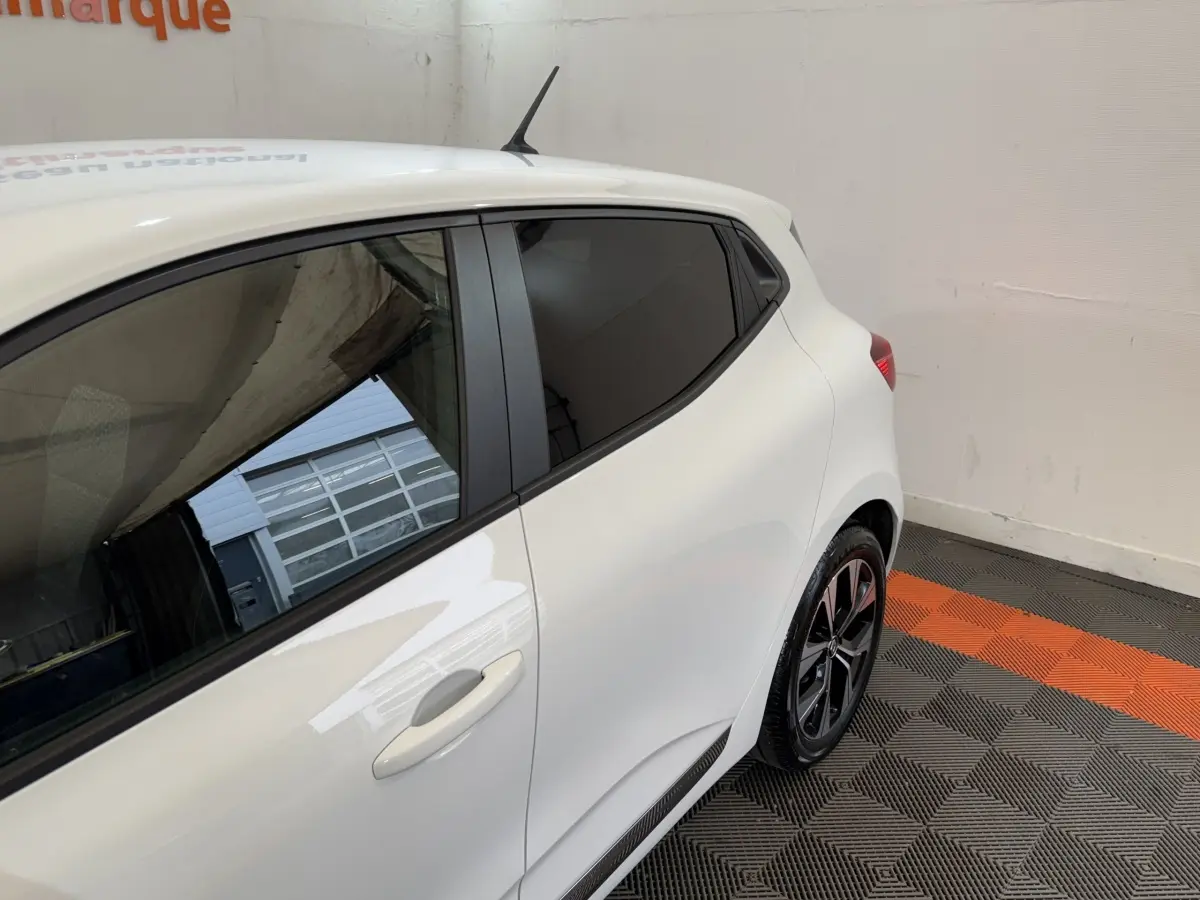 Vue 3/4 arrière côté droit d'une Renault Clio Business TCe 100 GPL blanche avec vitres teintées et jantes noires.