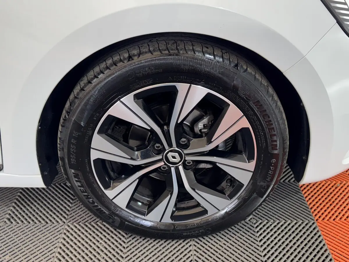 Gros plan sur la roue avant gauche d’une Renault Clio blanche, avec jante alliage bicolore et pneu Michelin.