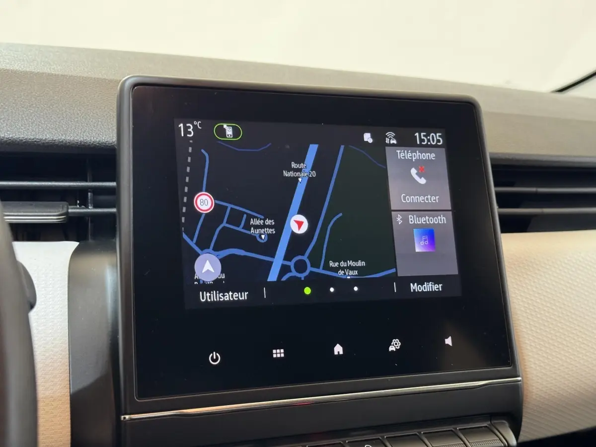 Écran tactile central du tableau de bord de la Renault Clio Business blanc, affichant la navigation GPS et options Bluetooth.