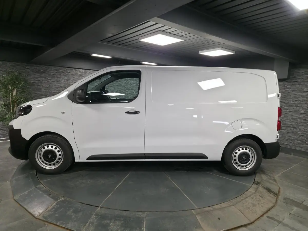 Vue de profil côté gauche d’un Opel Vivaro blanc 2025 utilitaire avec roues tôles et poignées noires.