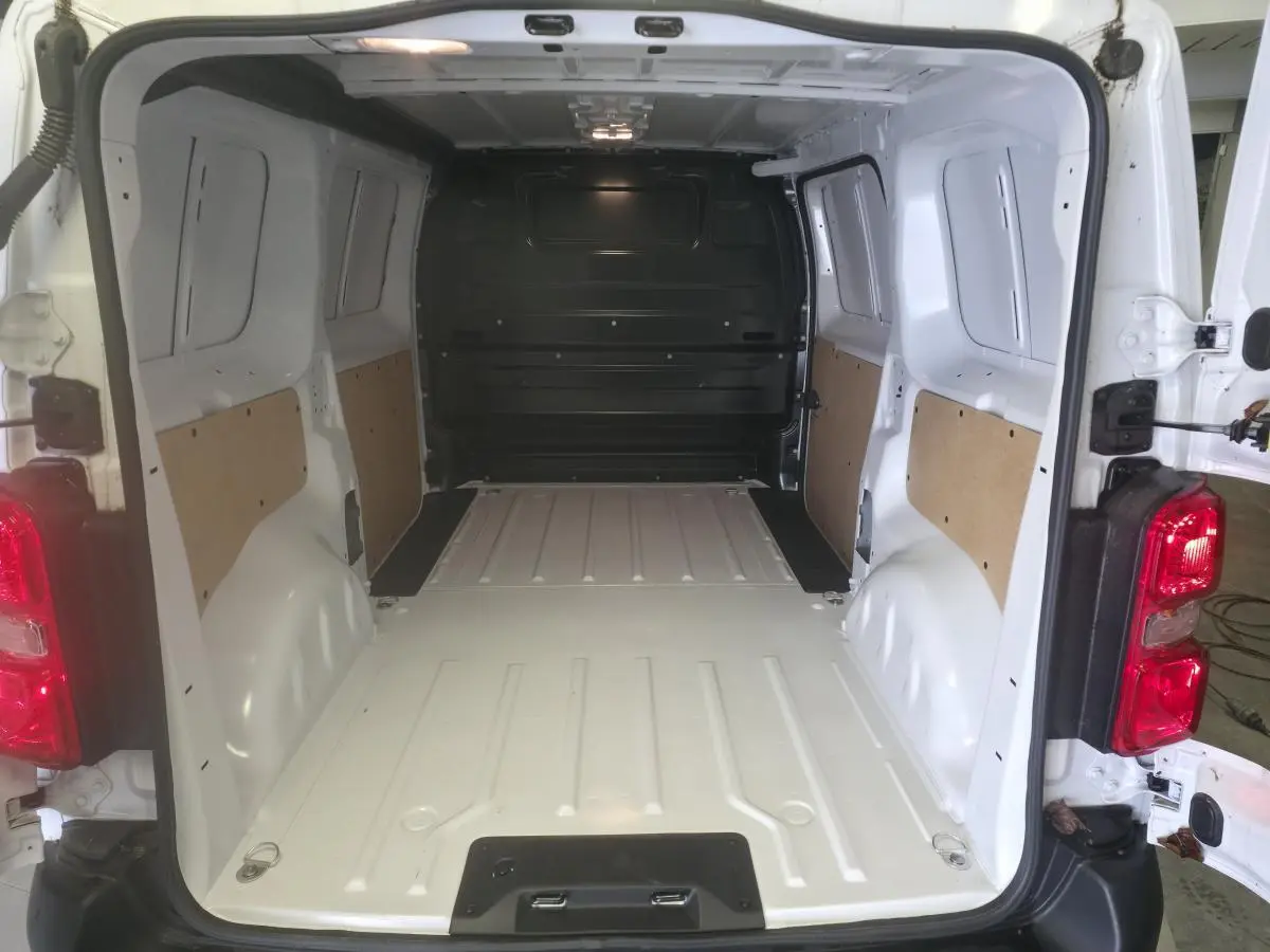 Vue arrière du fourgon blanc Opel Vivaro 2025, montrant l'espace de chargement vide avec parois partiellement protégées.