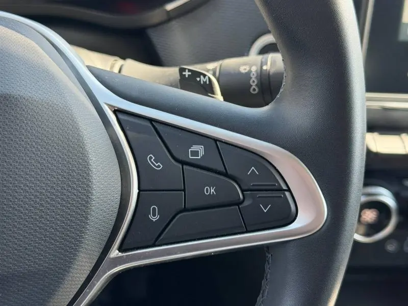 Gros plan sur les commandes au volant côté droit du Renault Arkana gris métallisé 2025, avec boutons multifonctions.