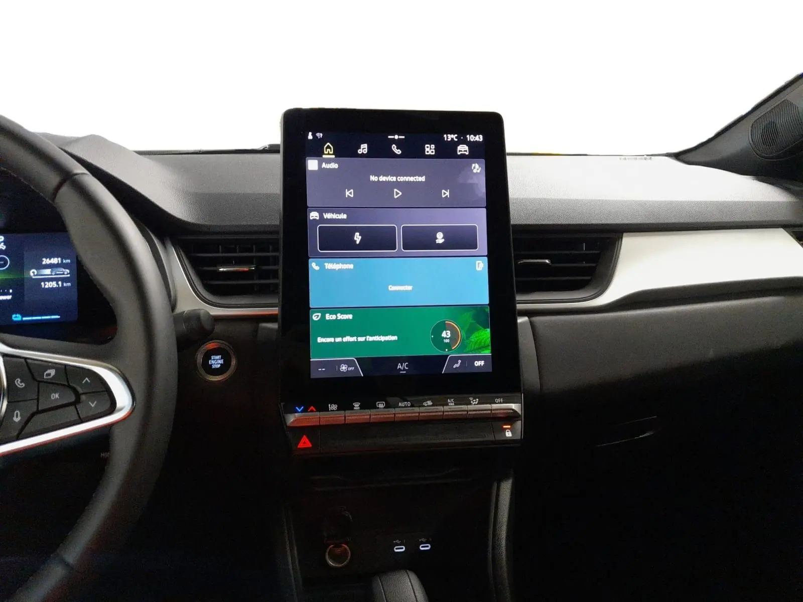 Vue intérieure centrée sur la console centrale tactile verticale du Renault Symbioz gris Cassiopée avec volant partiel à gauche.