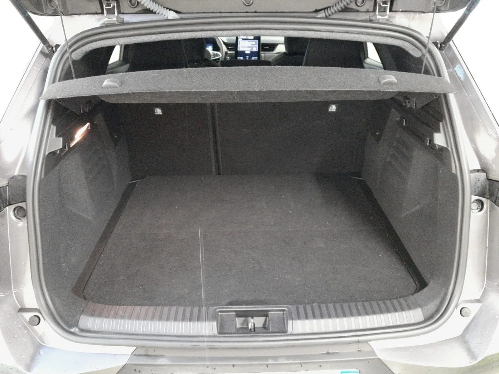 Coffre ouvert d’une Renault Symbioz gris cassiopée, vue arrière montrant l’espace de chargement et l’habitacle à l’avant.