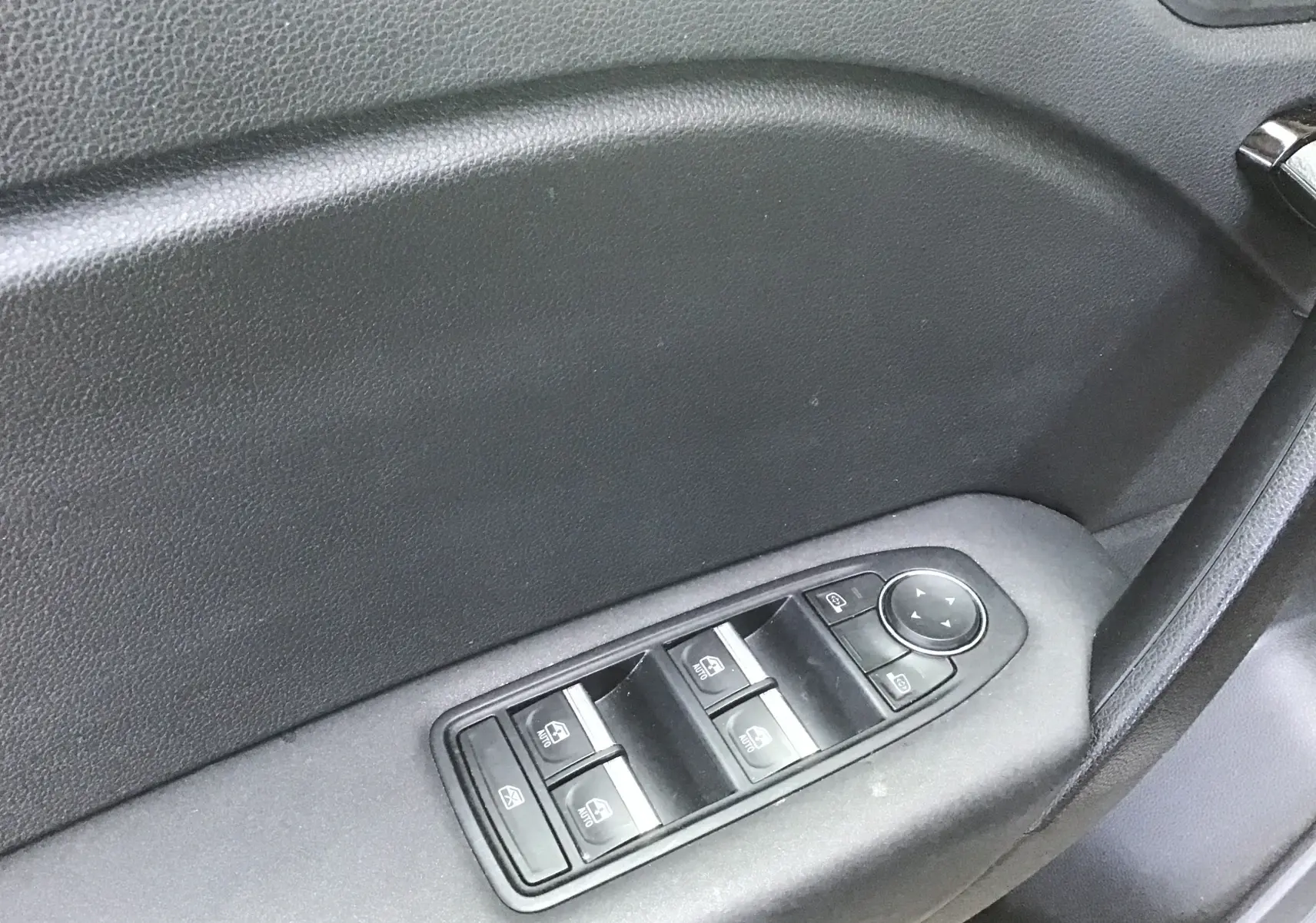 Gros plan sur les commandes de lève-vitres et réglage des rétroviseurs côté conducteur du Renault Symbioz gris Cassiopée 2025.