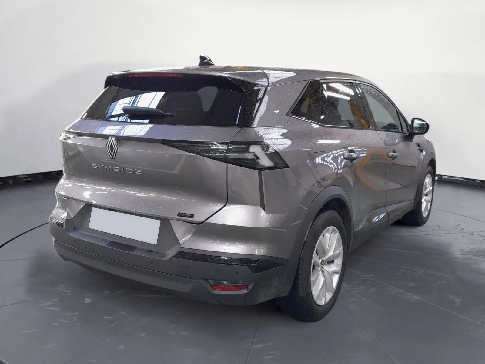Vue 3/4 arrière droite du Renault Symbioz gris Cassiopée, mettant en valeur ses lignes modernes et son logo distinctif à l'arrière.