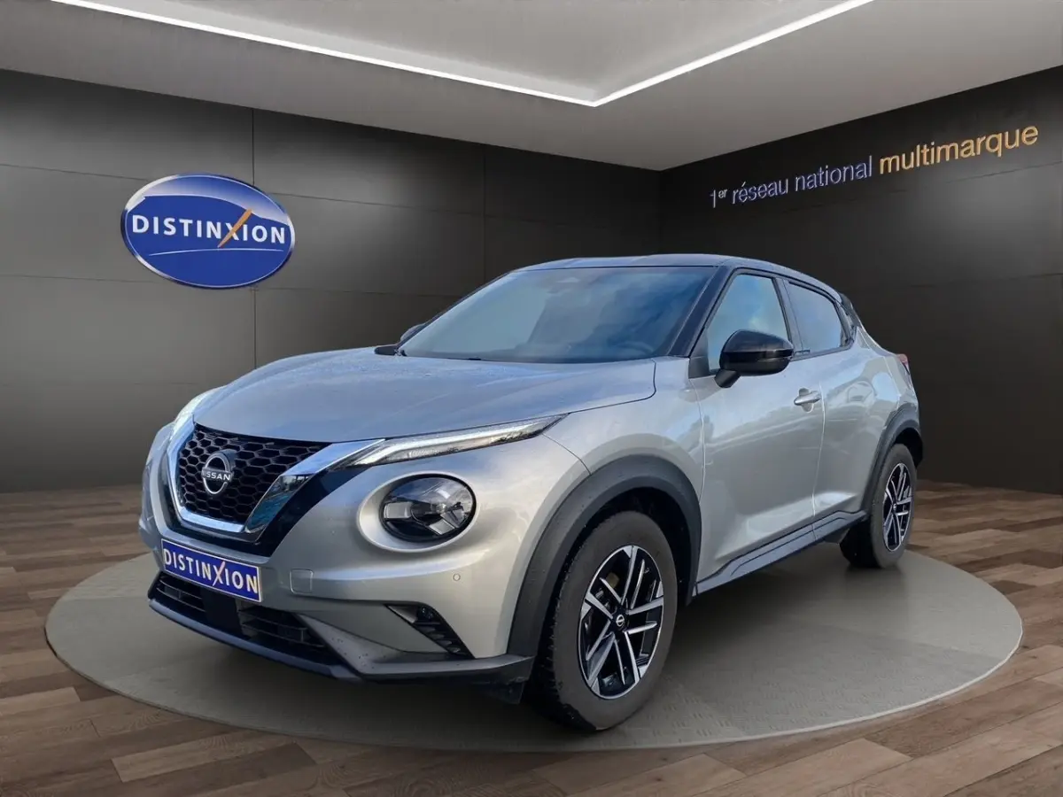 Nissan Juke gris clair en 3/4 avant droit, avec jantes alliage noires et toit noir contrasté.