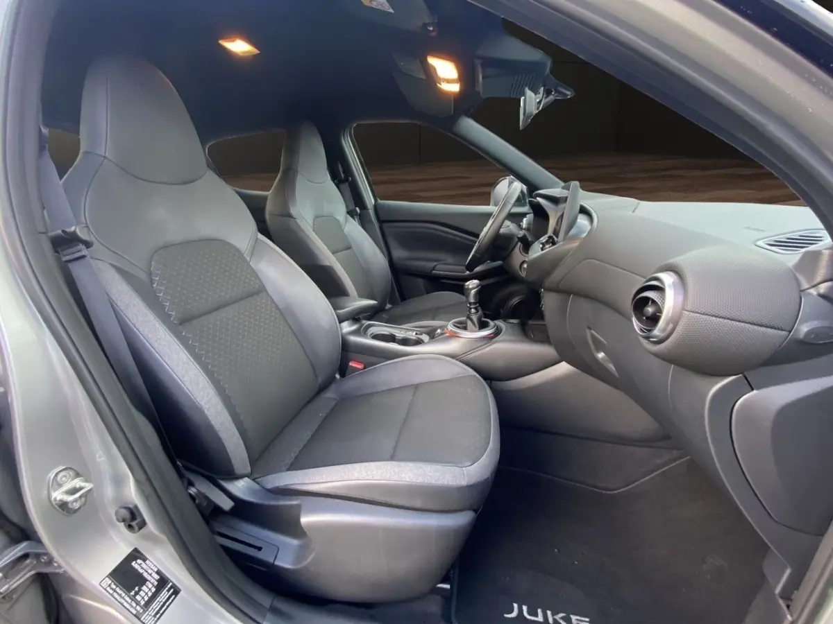 Vue intérieure côté conducteur du Nissan Juke gris clair 2025, montrant sièges avant et tableau de bord moderne.